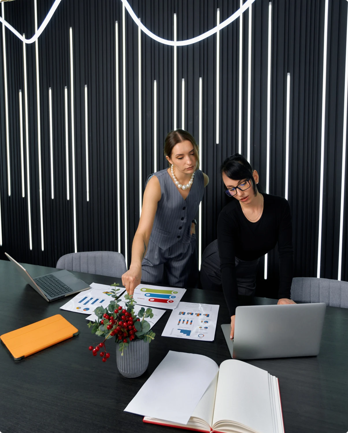 Two creative team members reviewing printed charts and layouts at a meeting table