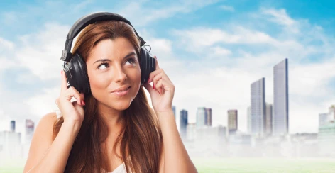 Woman listening on headphones against a city skyline
