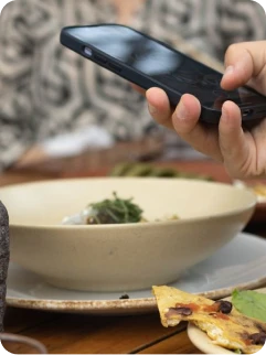 Customer holding a phone over a restaurant meal
